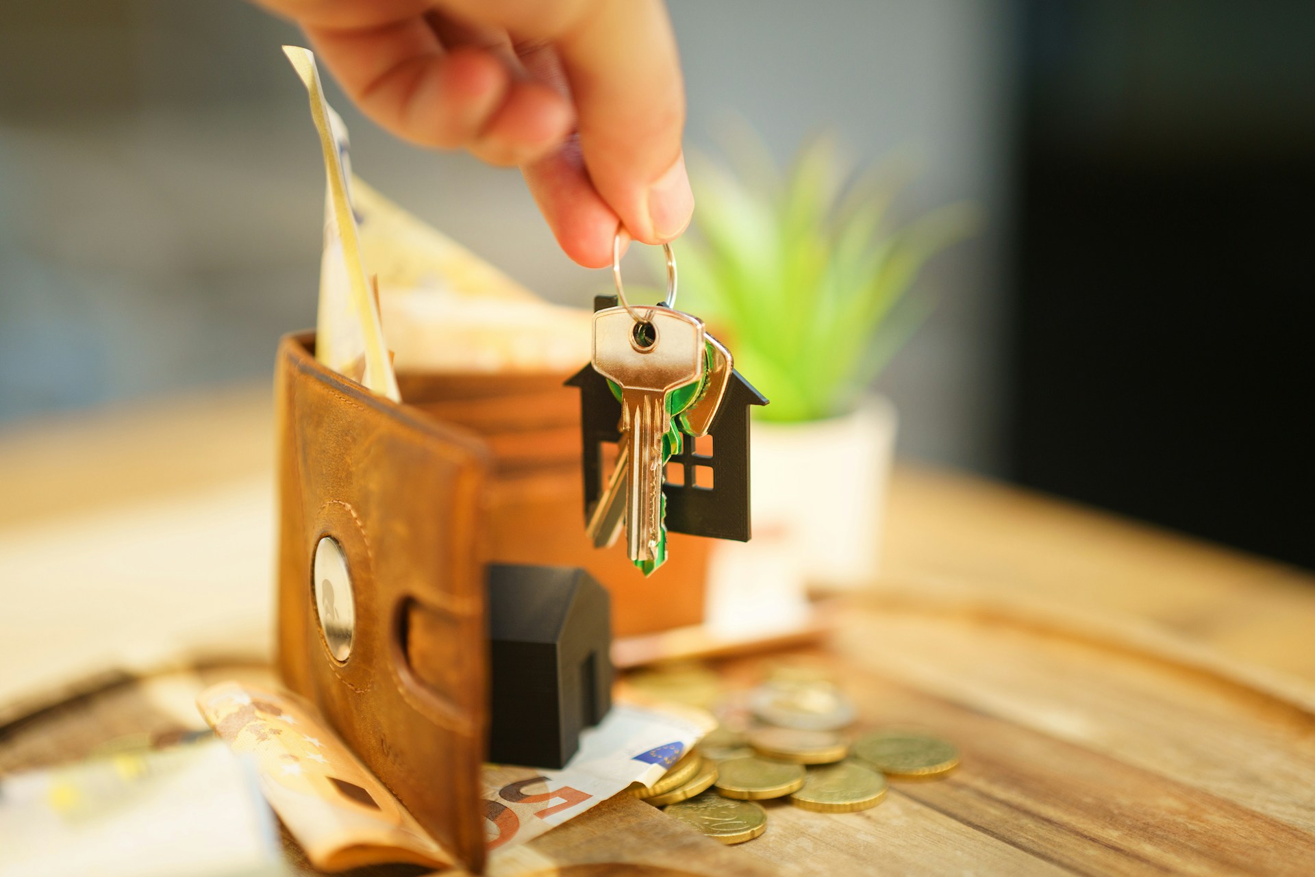 House keys dangling in front of a wallet and a scattering of cash